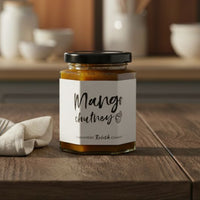 Jar of mango chutney on a wooden table with kitchen utensils in the background