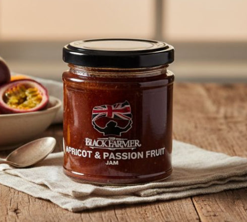 Jar of apricot and passion fruit jam on a wooden table with fruits in the background
