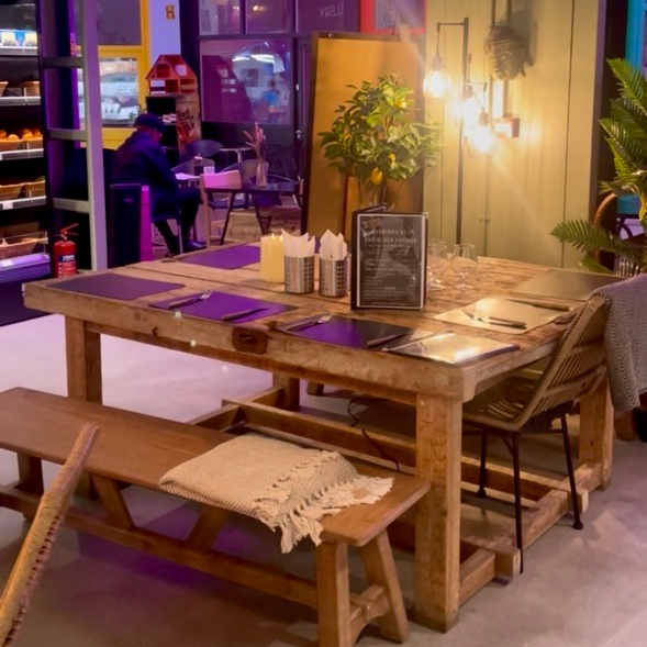 Wooden dining table with chairs and a bench in a colorful indoor setting.