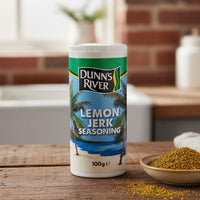 Dunns River Lemon Jerk Seasoning 100g shaker on a wooden table with spices and herbs.