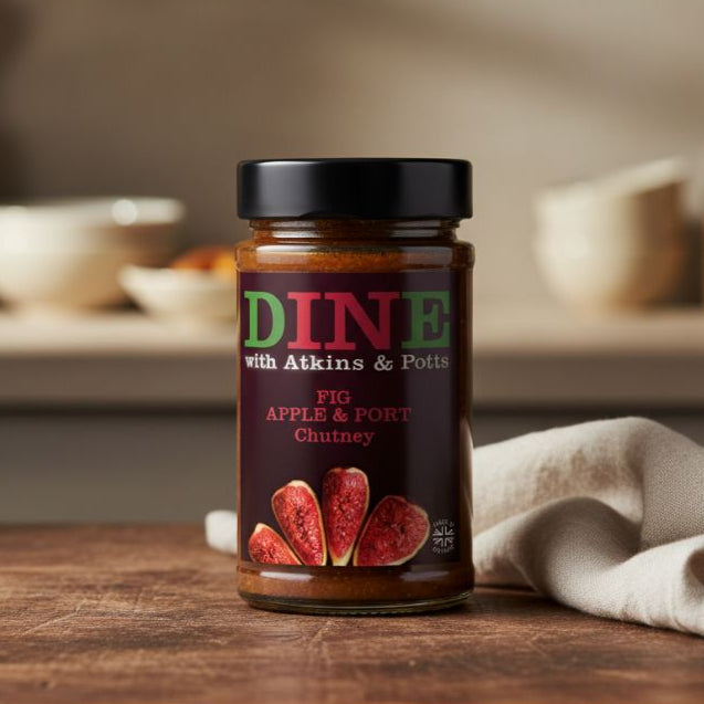 Jar of 'Dine with Atkins & Potts' fig apple and port chutney on a wooden surface.