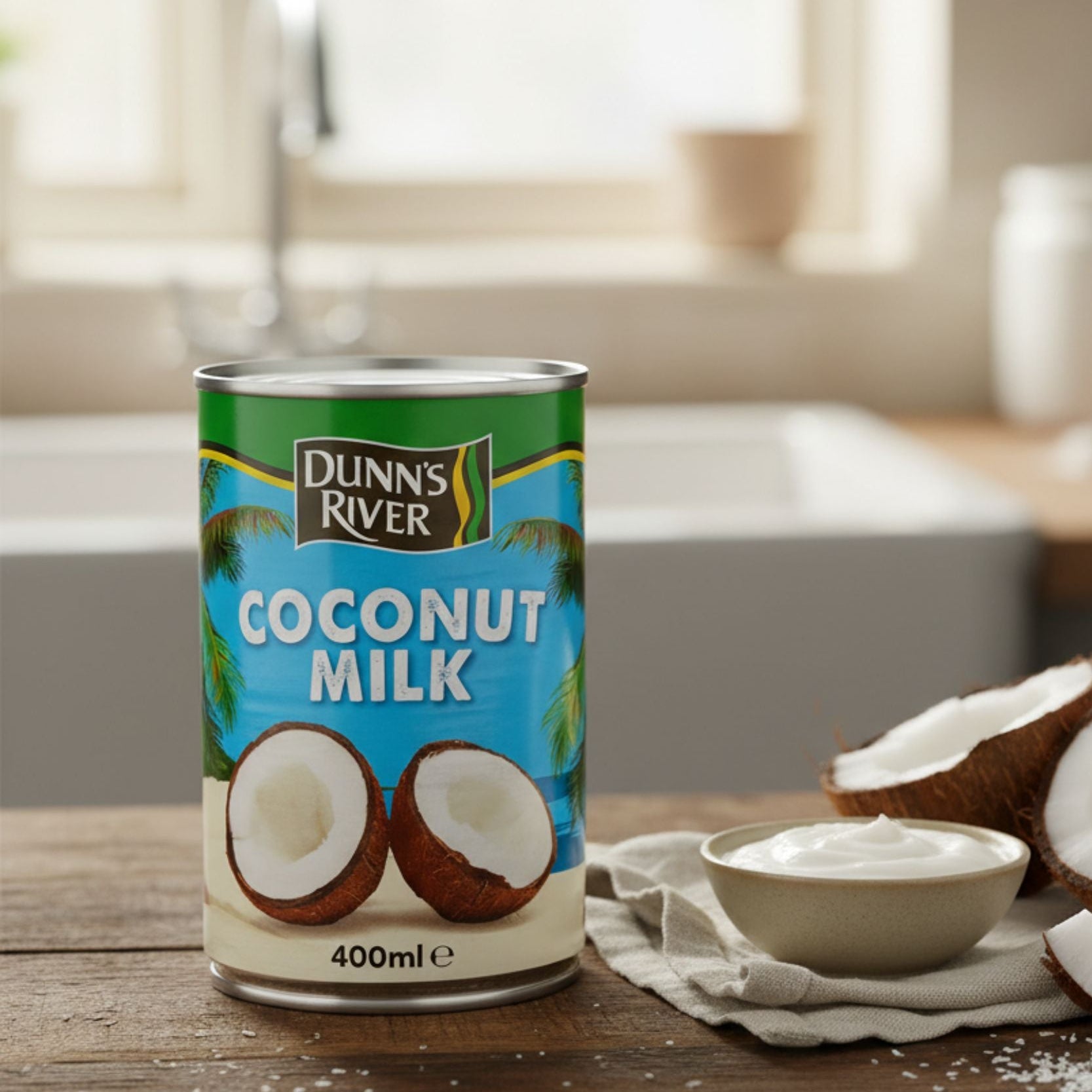 Can of Dunn's River coconut milk on a wooden table with coconuts and a bowl of coconut cream.