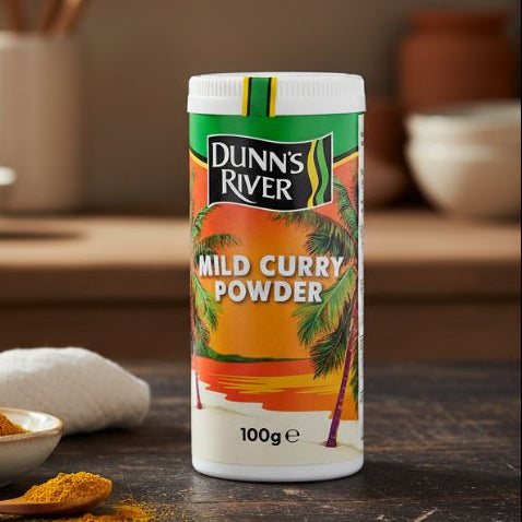 Dunns River Cock Flavoured Seasoning 100g shaker on wooden table with herbs and spices.