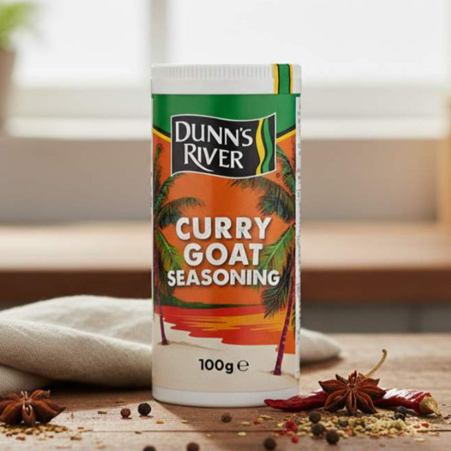 Dunn's River Curry Goat Seasoning container on a wooden surface with spices.