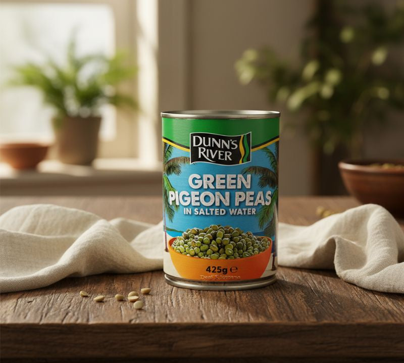 Can of Dunn's River Green Pigeon Peas on a wooden table with plants in the background