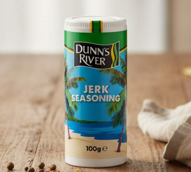Dunn's River jerk seasoning container on a wooden table with spices around