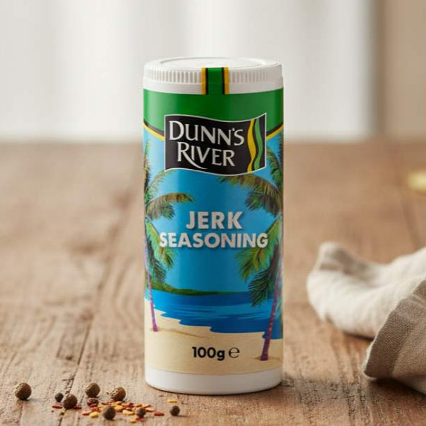 Dunn's River jerk seasoning container on a wooden table with spices around