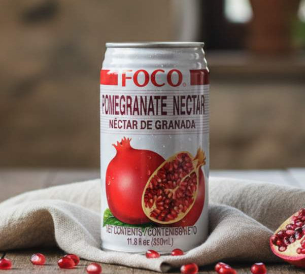 FOCO Pomegranate Drink 350ml — tropical pomegranate nectar can with fruit and seeds on rustic table.