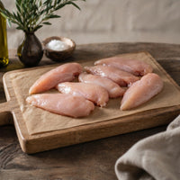 Raw chicken breasts on a wooden board.