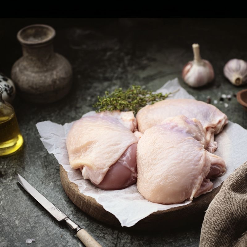 Free range British chicken thighs, bone-in and skin-on, on rustic wooden board — The Black Farmer