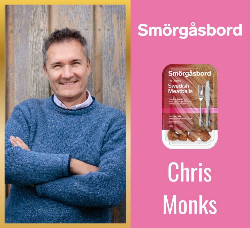 Man in blue sweater with Smörgös bord packaging on pink background