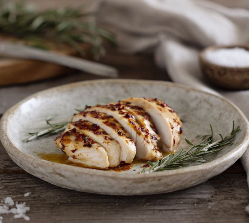 hot-and-spicy chicken breast fillets on a board with chillies and herbs – The Black Farmer.