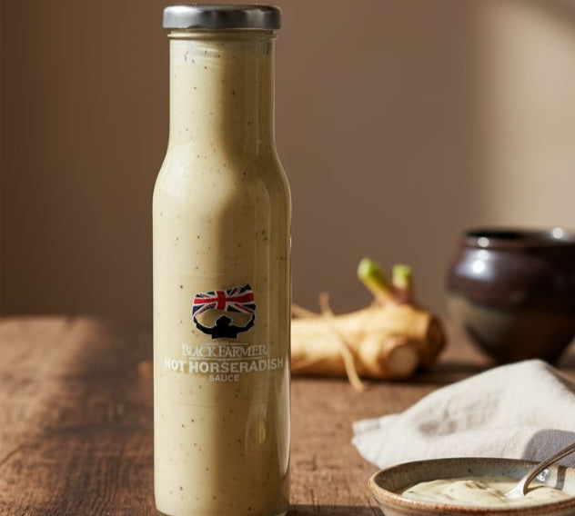 Bottle of horseradish sauce on a wooden surface with a bowl and spoon.