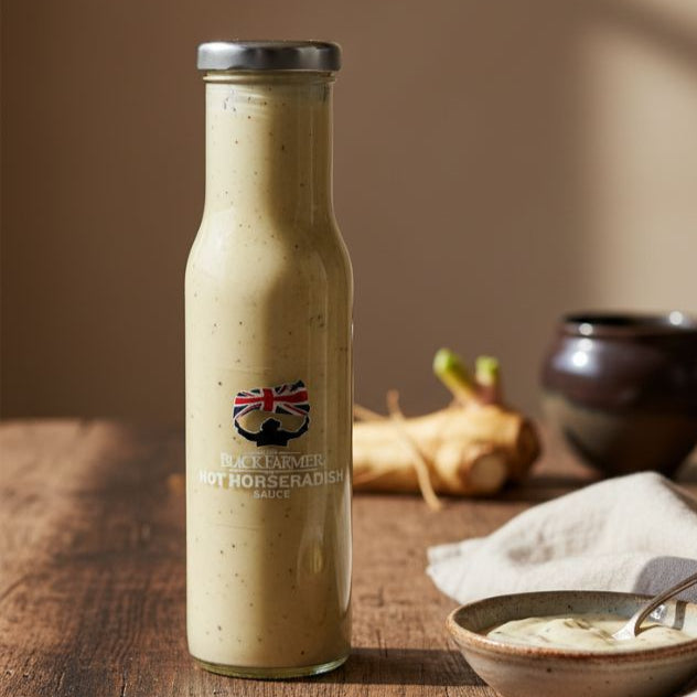 Bottle of horseradish sauce on a wooden surface with a bowl and spoon.