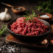 Ground meat in a wooden bowl with rosemary on a rustic background