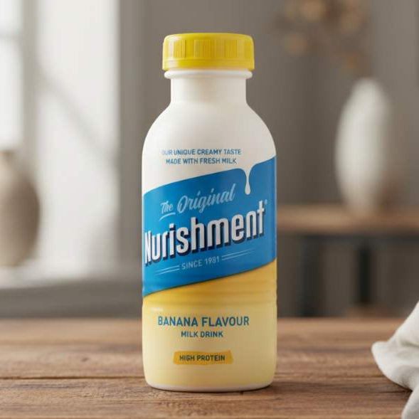Nurishment banana-flavored milk drink bottle on a wooden surface with a blurred indoor background