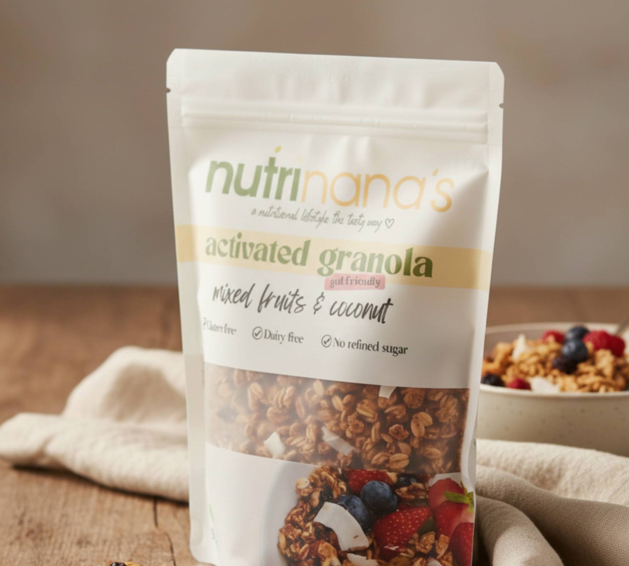Package of Nutrinana's activated granola with a bowl of granola and fruits in the background.