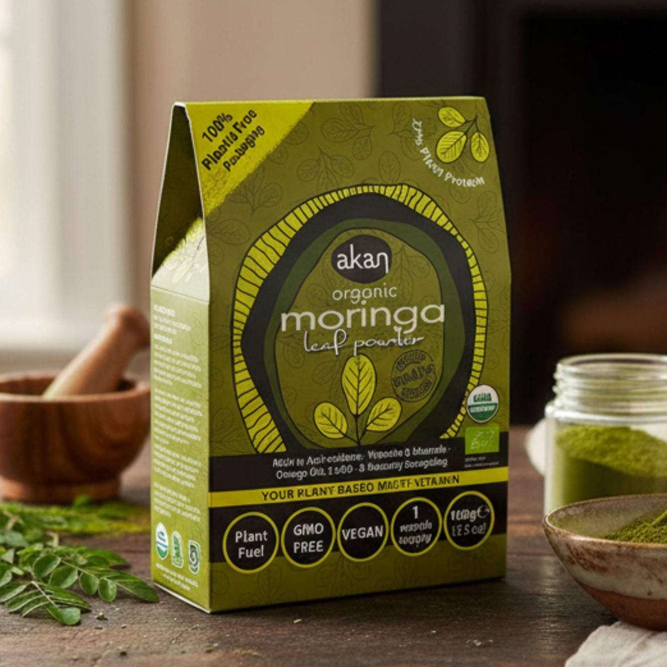 Akan organic moringa leaf powder packaging on a wooden table with a fireplace in the background