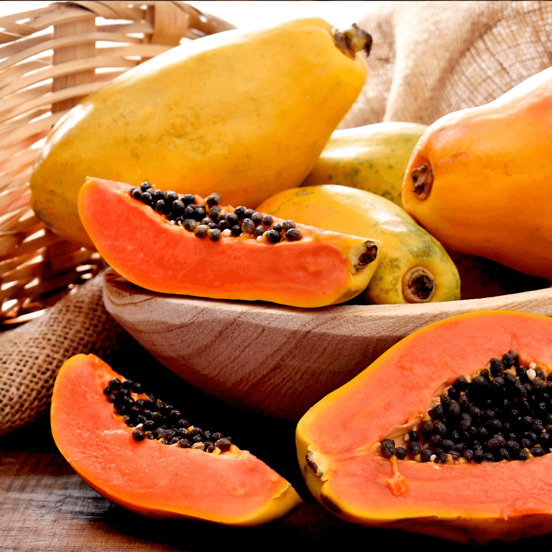 Papayas with a focus on a halved papaya on a wooden surface.