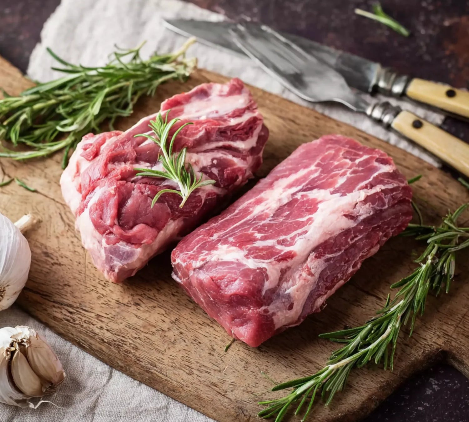 Raw British lamb neck fillet on board, rich marbling, ideal for slow-cooking and roasting.