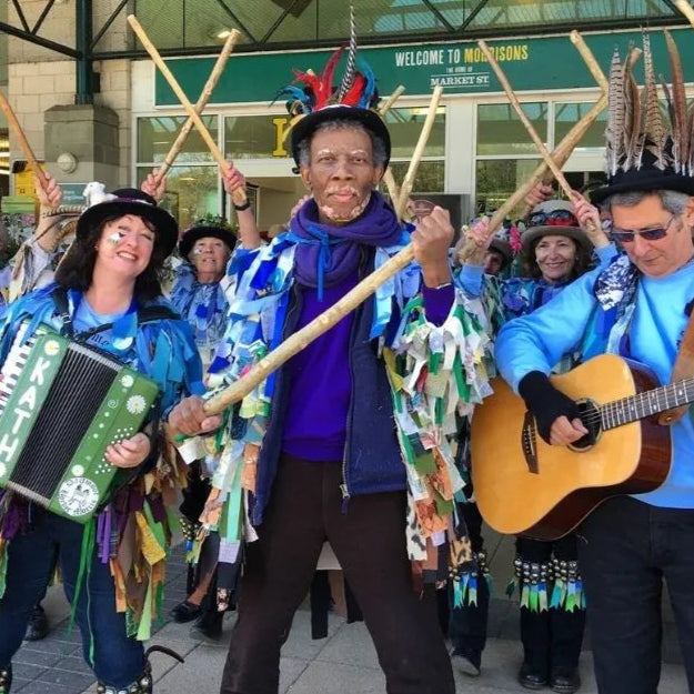 Group of people in colorful costumes with musical instruments in a public area.