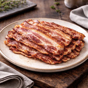 Stack of bacon on a ceramic plate with a wooden background