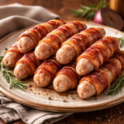 Bacon-wrapped sausages on a plate with herbs