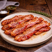 Slices of bacon on a ceramic plate with a wooden background