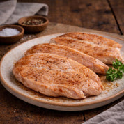 Three seasoned chicken breasts on a ceramic plate with a wooden background