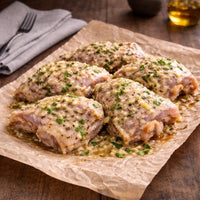 Raw chicken thighs with herbs and spices on a dark slate board