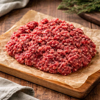 Ground meat in a wooden bowl with rosemary on a rustic background