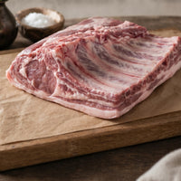 raw lamb breast bone-in on a wooden board