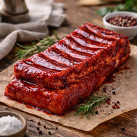 Slab of extra-meaty pork ribs brushed with red Char Siu glaze on a board with dipping sauce – The Black Farmer.