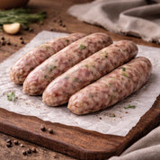 Raw sausages on a wooden cutting board with herbs and spices