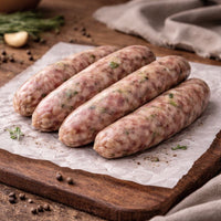 Raw sausages on a wooden cutting board with herbs and spices