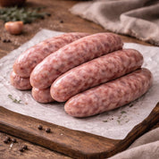 Raw sausages on a wooden cutting board with garlic and peppercorns.