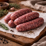 Raw venison sausages on a wooden cutting board with a rustic background