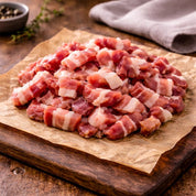Smoked bacon lardons on wooden board with seasoning, raw premium British pork