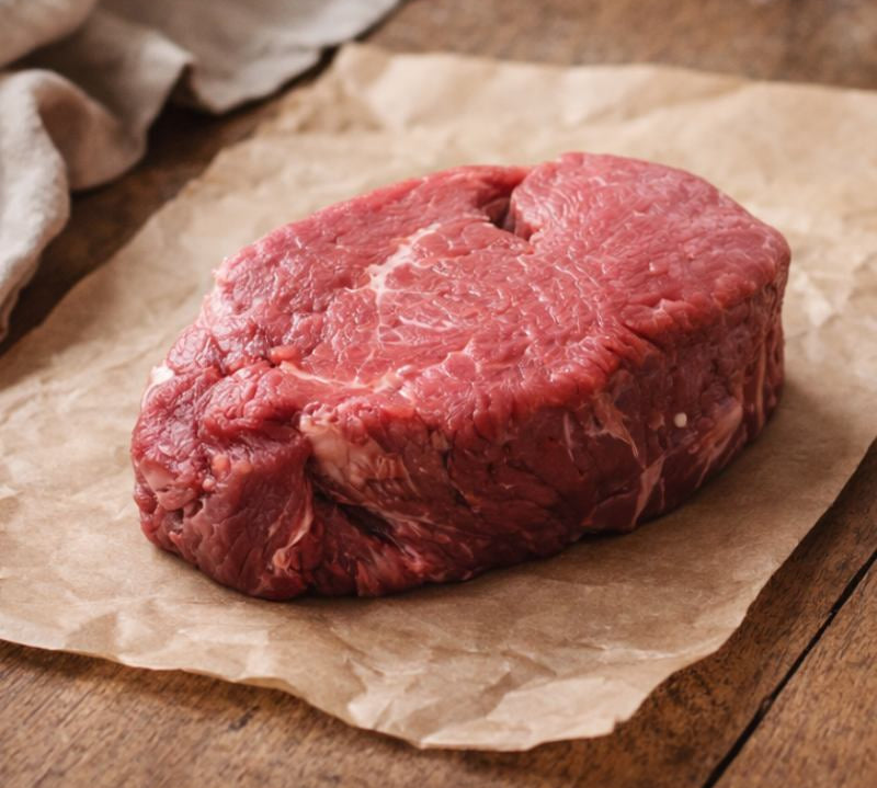 Raw steak on brown paper with a wooden background