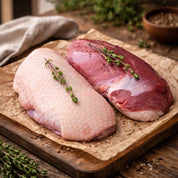 Raw duck and pork on a wooden cutting board with herbs and spices.