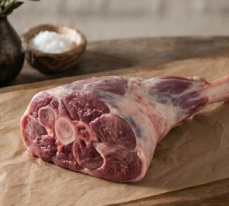 Raw meat with string on a wooden cutting board with rosemary sprigs
