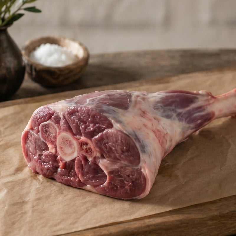 Raw meat with string on a wooden cutting board with rosemary sprigs