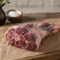 Raw meat with string on a wooden cutting board with rosemary sprigs