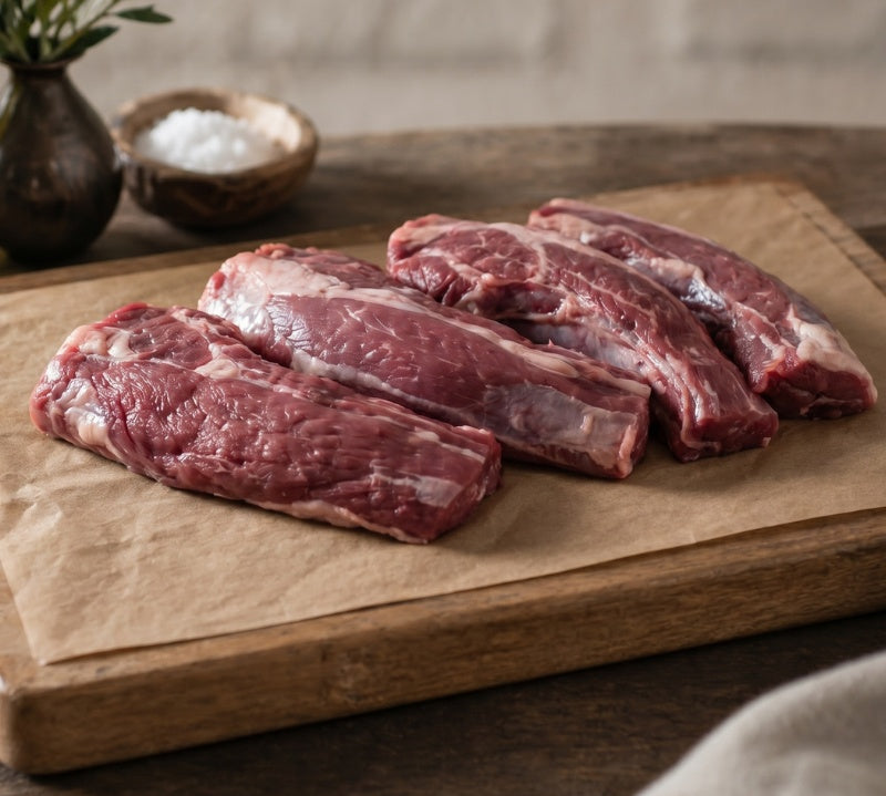 Raw British lamb neck fillet on board, rich marbling, ideal for slow-cooking and roasting.