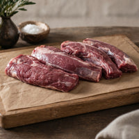 Raw British lamb neck fillet on board, rich marbling, ideal for slow-cooking and roasting.