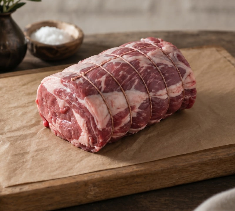 Boneless rolled lamb shoulder on wooden board, British lamb cut ideal for roasting and slow cooking.