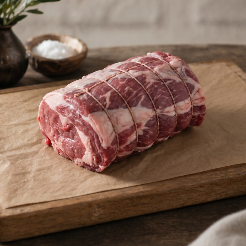 Boneless rolled lamb shoulder on wooden board, British lamb cut ideal for roasting and slow cooking.