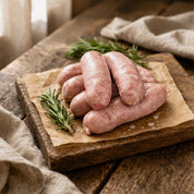 Raw premium pork sausages on a wooden cutting board with herbs and spices