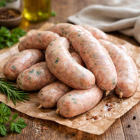 Raw sausages on a wooden cutting board with garlic and peppercorns.